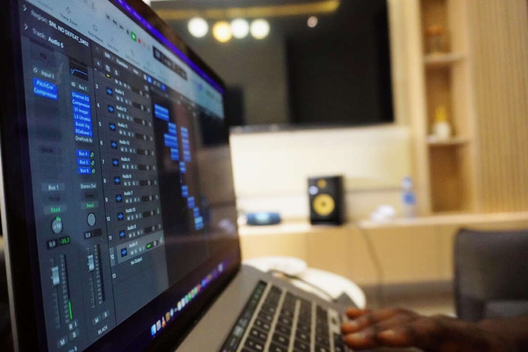 Hands typing on laptop with studio monitoring software
